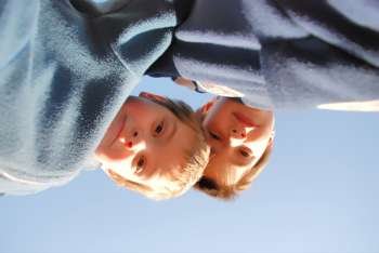 two boys play outside. They are looking down at us and we are on the ground 