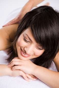 A happy beautiful asian woman getting a massage in a spa salon