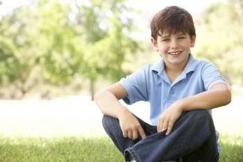 Portrait Of Young Boy Sitting In Park