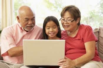 Grandparents And Grandaughter Using Laptop Computer At Home