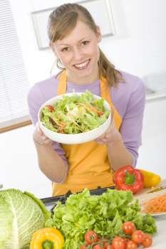 Beautiful young woman making vegetarian vegetable salad 