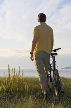 Man standing by his cycle at the sea 