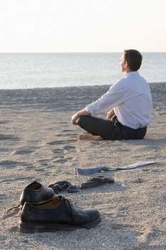 Businessman relaxing on beach - Focus on the shoes in the foreground 