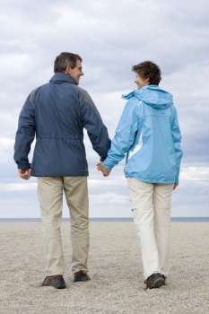 Smiling mature couple walking hand in hand on a beach 