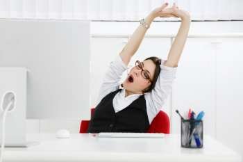 Young businesswoman sitting at desk yawning. Copy space 