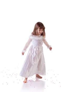 Cute little girl dancing on the floor with heart shaped confetti 