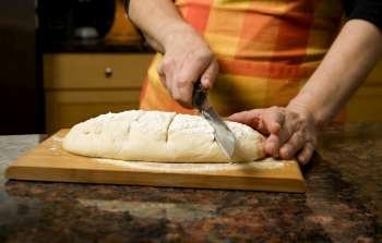 Adding cut to unbaked bread dough with serrated knife 