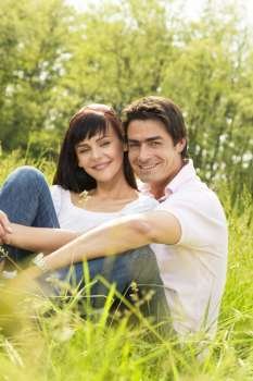 Couple lying in grass, smiling and hugging 