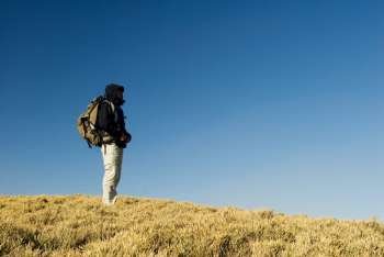 A backpacker walk on a yellow grassland in mountain. 