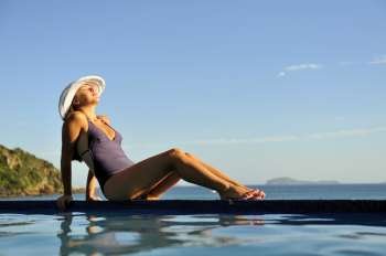 Woman relaxing on a swimming pool with a sea view 