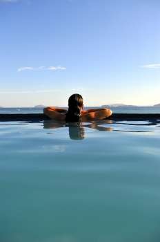 Woman relaxing on a swimming pool with a sea view 