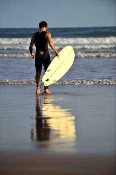 Surfer boy walking on the beach in Buzios, Brazil 