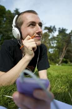 Man listening to the music in a park with white headphones 
