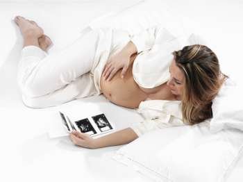A shot of a pregnant woman carrying her child´s ultrasound picture