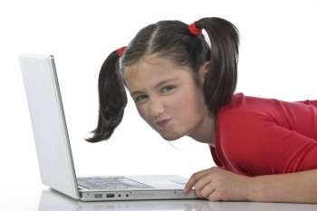 Adorable caucasian little girl lying with laptop 