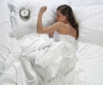 Woman in bed with alarm clock 