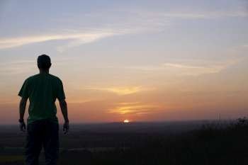 Man standing and looking at sunset on horizon