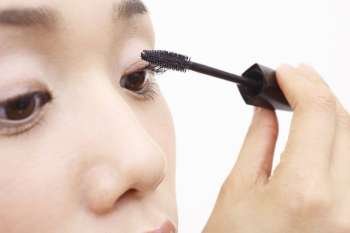 Japanese woman applying mascara to eyelashes