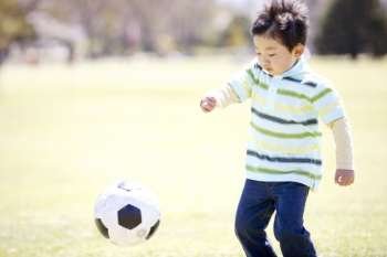 Japanese boy playing soccer in the park
