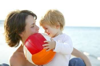 Mother and son on the winter sea, happy together with football ball