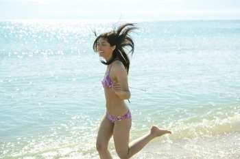 beautiful woman running on the beach, purple bikini