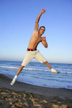 Handsome winner young man jumping on the blue beach