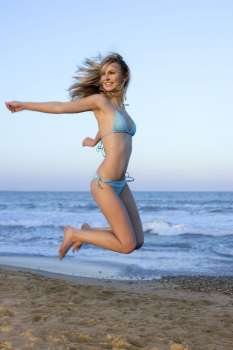 Beautiful blond girl jumping bikini on the beach