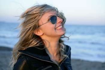 Blond girl with retro sunglasses on the blue beach, wind