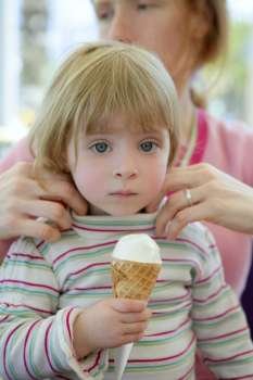 Beautiful toddler blond little girl eating ice cream, mother taking care