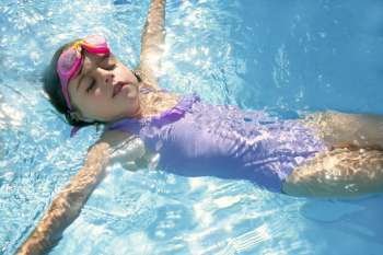 Beautiful girl swimming on blue pool with pink goggles