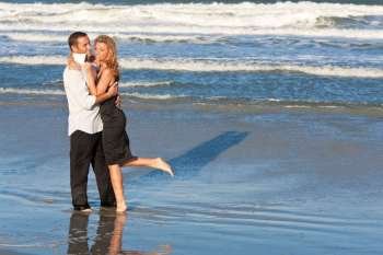 A young man and woman embracing as a romantic couple on a beach
