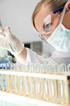 A female scientific researcher or doctor looking at a test tube of clear solution in a laboratory.
