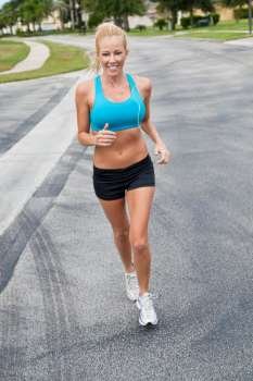 A beautiful fit and healthy blond woman road running while listening to music on her portable mp3 player
