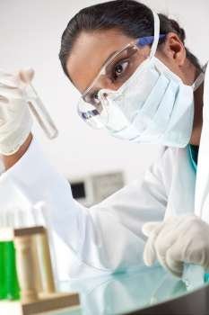 A female Asian medical or scientific researcher or doctor looking at a test tube of clear solution or liquid in a laboratory.