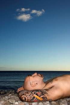 Tattooed Man Lying on Beach