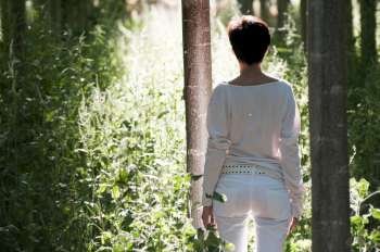 Woman walking into a green woodland  