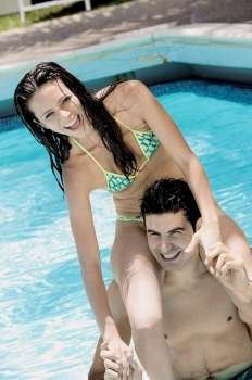 Young man carrying a young woman on his shoulders in a swimming pool