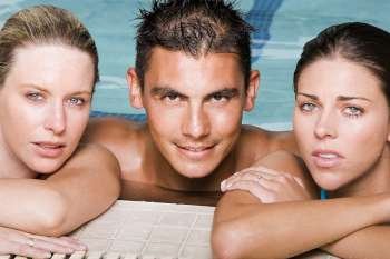 Portrait of a young man and two young women leaning at the edge of a swimming pool