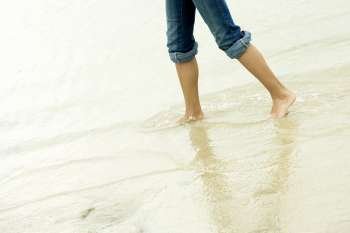 Low section view of a girl wading in water on the beach