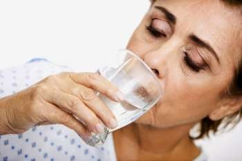 Close-up of a senior woman drinking water from a glass