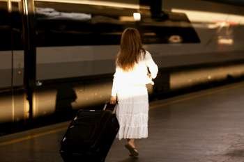 Rear view of a woman pulling her luggage at a railroad station platform, Rome, Italy