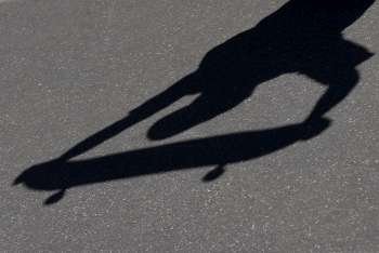 High angle view of shadow of a person holding a skateboard