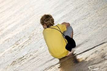 Rear view of a boy squatting on the beach