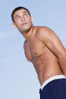 Low angle view of a bare chested young man looking up