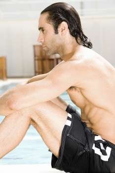 Side profile of a mid adult man sitting at the poolside