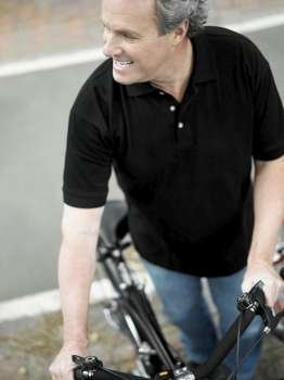 High angle view of a mature man standing with a bicycle and smiling