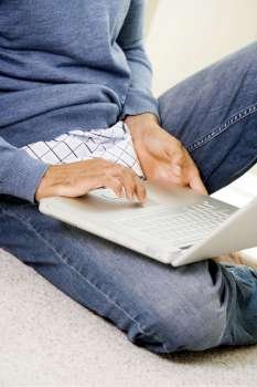 Mid section view of a mid adult man using a laptop