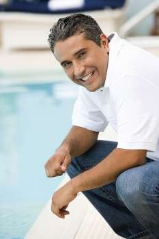 Portrait of a mid adult man crouching at the poolside