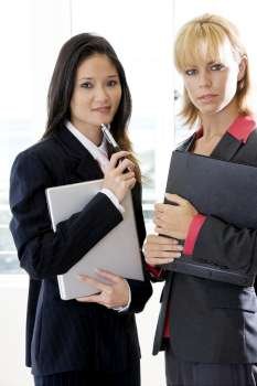 Portrait of two businesswomen holding a file and a laptop