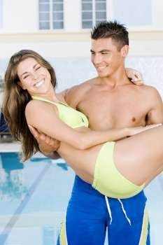 Young man carrying a young woman at the poolside
